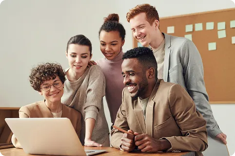 Diverse team of financial professionals collaborating and smiling around a laptop